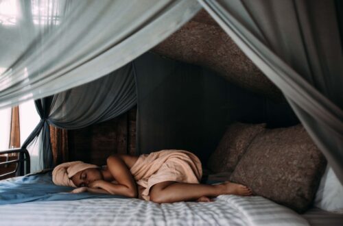 woman lying on bed wrapped around a towel