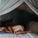 woman lying on bed wrapped around a towel